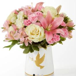 Pink and cream bouquet in a white vase with a gold dove design