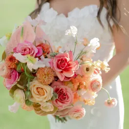 Bride holding a pastel bouquet of roses, ranunculus, and orchids