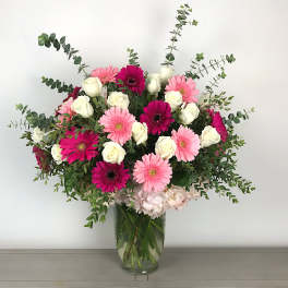 Pink gerbera daisies and white roses in a glass vase