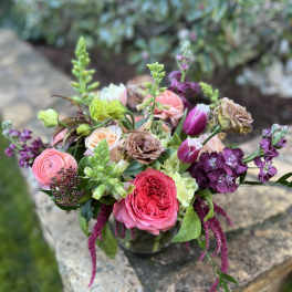 Mixed bouquet of pink, purple, and peach flowers in a glass vase