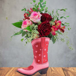 Pink and red roses with accent flowers in a heart-patterned pink cowboy boot vase