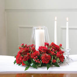 Red floral centerpiece with three white candles in glass holders