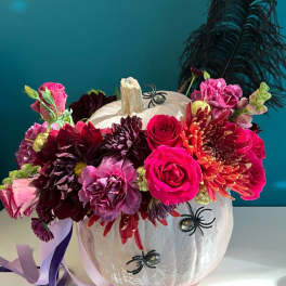 Floral arrangement in a white pumpkin with pink and burgundy blooms