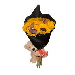 Sunflower bouquet wrapped in black paper with a teddy bear and ribbon