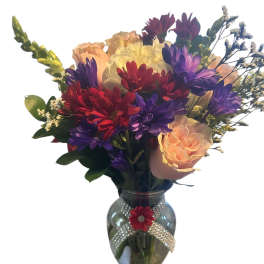 Mixed bouquet of roses and daisies in a glass vase with a rhinestone ribbon