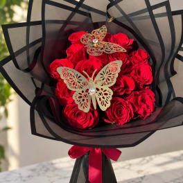 Bouquet of red roses wrapped in black paper with butterfly decorations