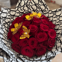 Bouquet of red roses wrapped in black-and-white patterned paper with yellow butterfly accents
