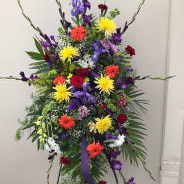 Tall standing floral spray with multicolored blooms and purple ribbon