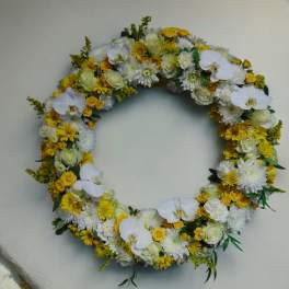 Large circular wreath of white orchids, roses, and yellow chrysanthemums arranged in a full ring