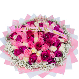 Large round bouquet of pink and white roses with baby's breath, tiara, and 'Proud Of You Mom' ribbon wrap