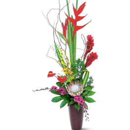 Tall tropical flower arrangement in a dark vase with red and pink blooms