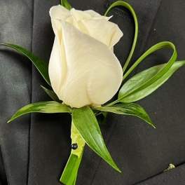 White rose boutonniere with green leaves on a dark suit