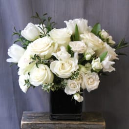 White roses and tulips arranged in a black square vase