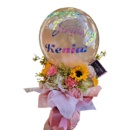 Birthday bouquet with sunflowers, pink roses, and carnations topped with a clear balloon that says Happy Birthday Kenia