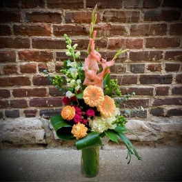 Tall bouquet of peach and pink flowers in a clear glass vase