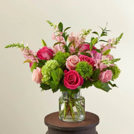 Mixed pink rose and green accent flower arrangement in a clear glass vase
