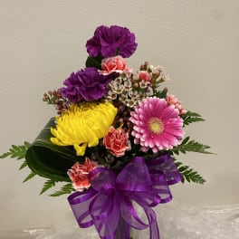 Colorful bouquet of carnations and a pink gerbera daisy in a glass vase