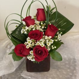 Red roses with white filler flowers in a dark vase