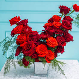 Red and orange roses in a clear square vase