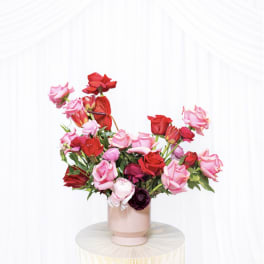 Pink and red rose arrangement in a blush vase