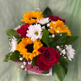 Bouquet of red roses, sunflowers, and white daisies in a gift box