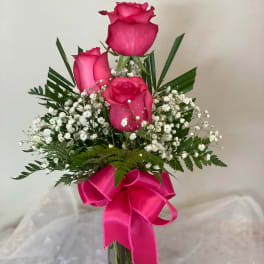 Pink roses in a clear glass vase with a bright ribbon
