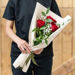 Bouquet of red roses with baby's breath in white paper