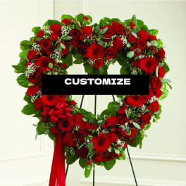 Heart-shaped red floral wreath on a stand with a ribbon bow