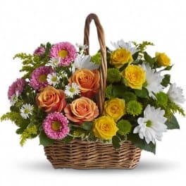 Wicker basket of orange and yellow roses with white daisies, pink asters, and green button mums