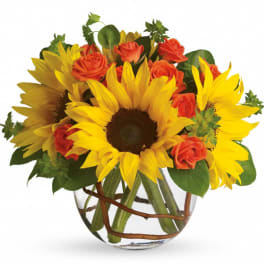 Sunflower and orange rose arrangement in a round clear glass vase