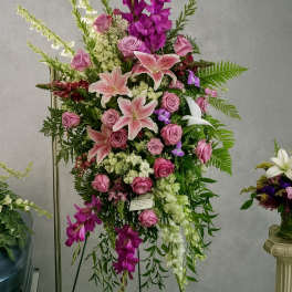 Tall pink and white standing spray with roses and lilies displayed on a metal easel