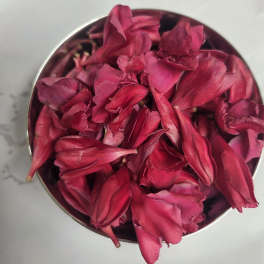 Bowl of deep pink rose petals on a light surface
