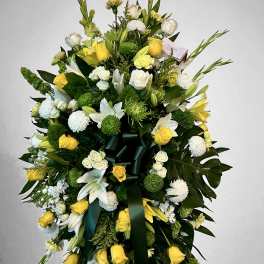 Tall yellow and white standing spray with roses, lilies, mums and dark green ribbon on an easel