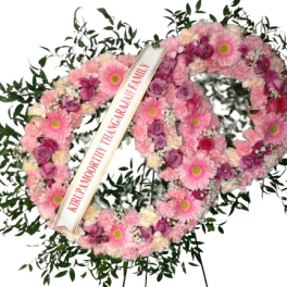 Pink floral funeral wreath with a condolence ribbon