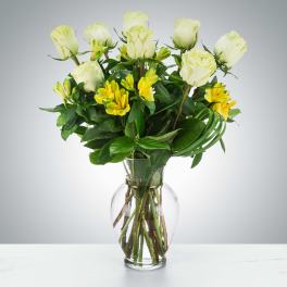 Vase arrangement of pale white roses and yellow alstroemeria in a clear glass vase
