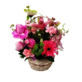 Mixed pink and red flowers arranged in a woven basket