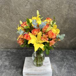 Yellow lilies and orange roses in a glass vase