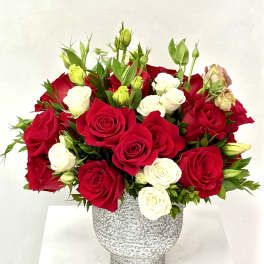 Arrangement of red and white roses with buds in a gray textured ceramic vase.