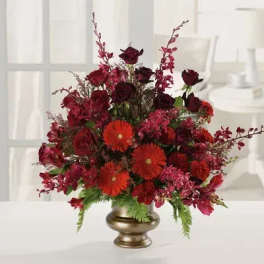 Red roses and orange gerbera daisies in a gold vase