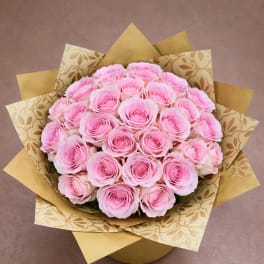 Bouquet of pink roses wrapped in patterned gold paper