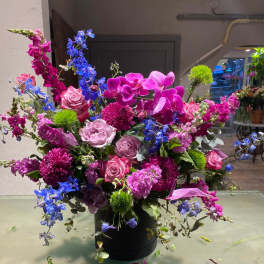 Large bouquet of pink, purple, and blue flowers in a black container