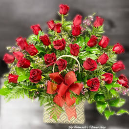 Large arrangement of red roses in a woven basket with a red bow
