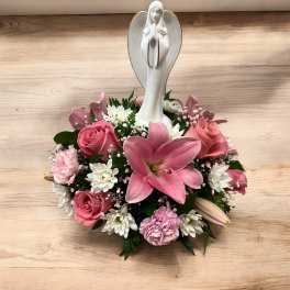 Low pink and white flower arrangement with a white angel figurine in the center