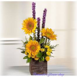 Tall sunflower and yellow mum arrangement with purple accents in a square wooden vase