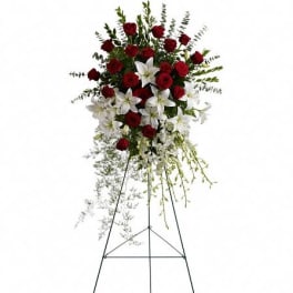 Tall standing spray of red roses and white lilies on a metal easel