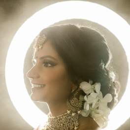 Bride in profile with white flowers in her hair and ornate jewelry