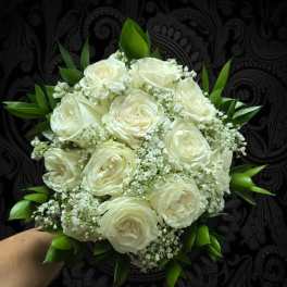 Bouquet of white roses with small white filler flowers and green leaves