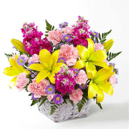 Basket of yellow lilies, pink carnations, and purple daisies