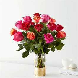 Bouquet of pink, red, and orange roses in a clear glass vase