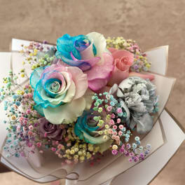 Bouquet of pastel rainbow roses with colorful baby's breath wrapped in white paper